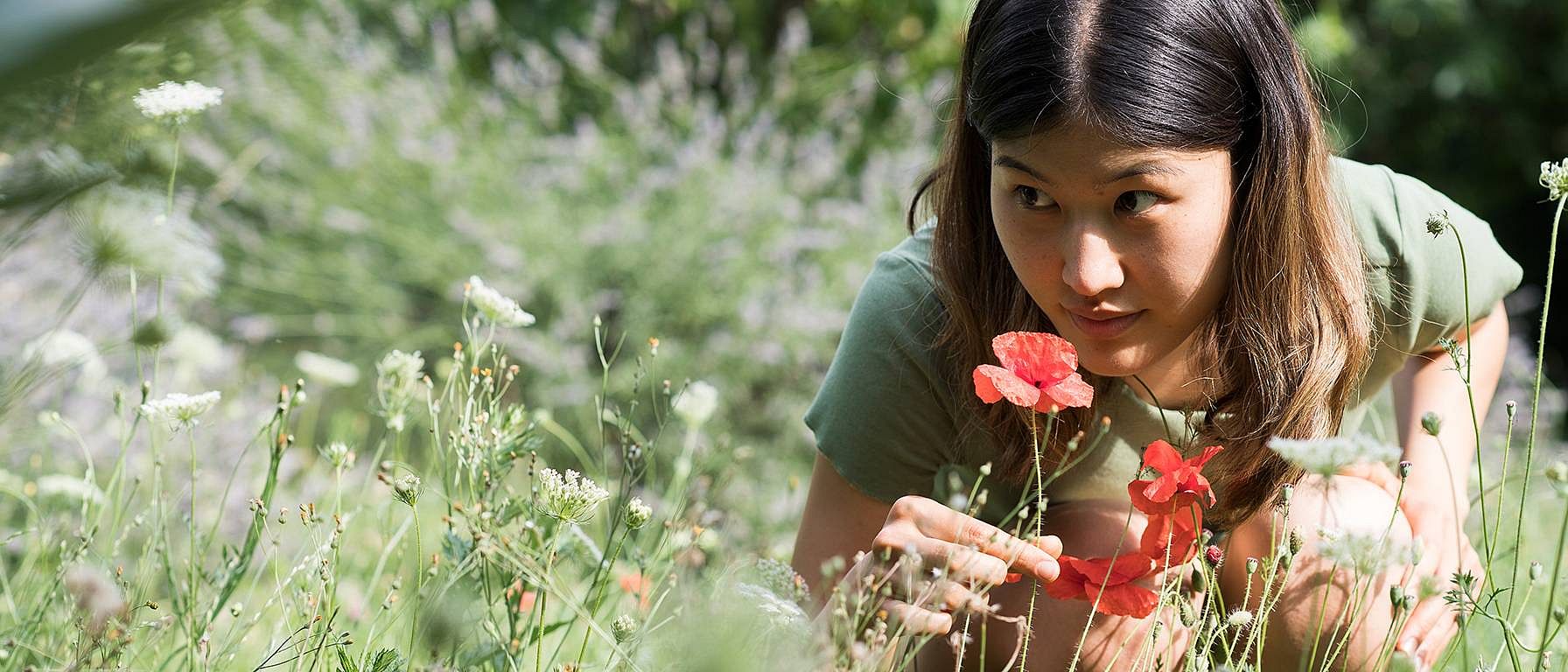 woman smelling flowers in a field