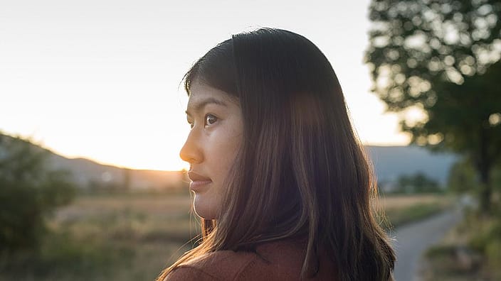 woman with dark hair blowing in wind at sunset