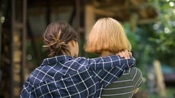 girl in flannel shirt with arm around a friend