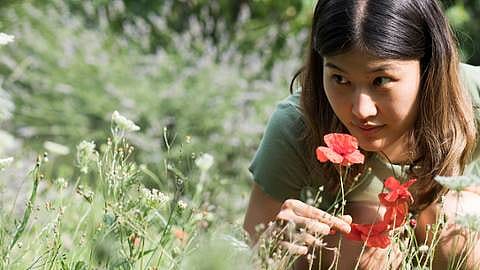 woman smelling flowers in a field