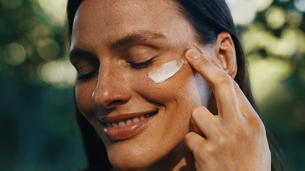 woman applying plumping day cream to cheek